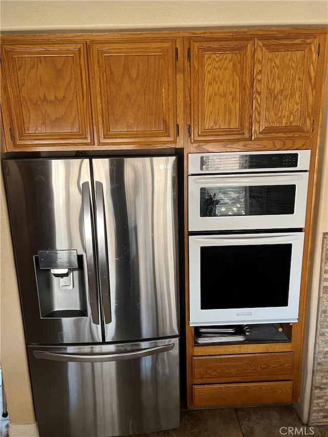 kitchen featuring brown cabinets, double oven, and stainless steel refrigerator with ice dispenser