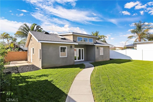 rear view of house featuring french doors, a fenced backyard, a yard, and stucco siding