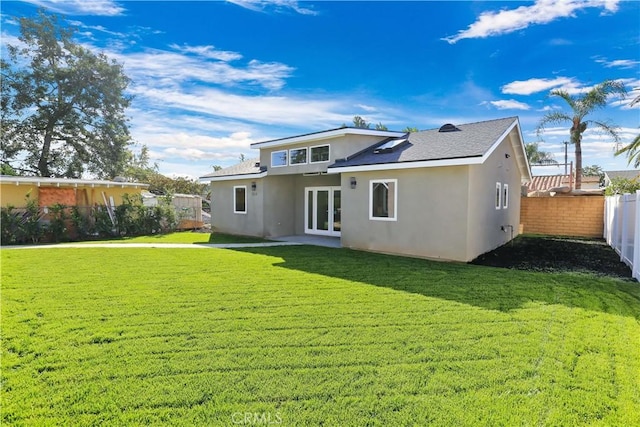 rear view of property featuring fence private yard, french doors, a yard, and stucco siding