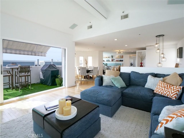 living area with high vaulted ceiling, light wood-type flooring, visible vents, and beamed ceiling