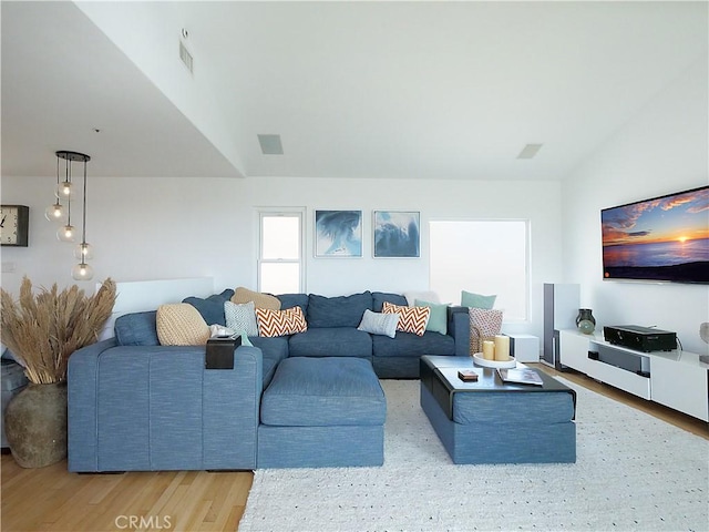 living area with lofted ceiling, wood finished floors, and visible vents