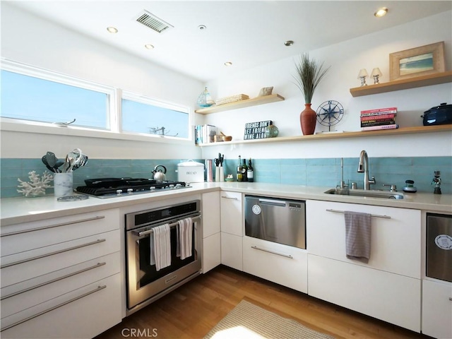 kitchen with open shelves, appliances with stainless steel finishes, a sink, and white cabinets