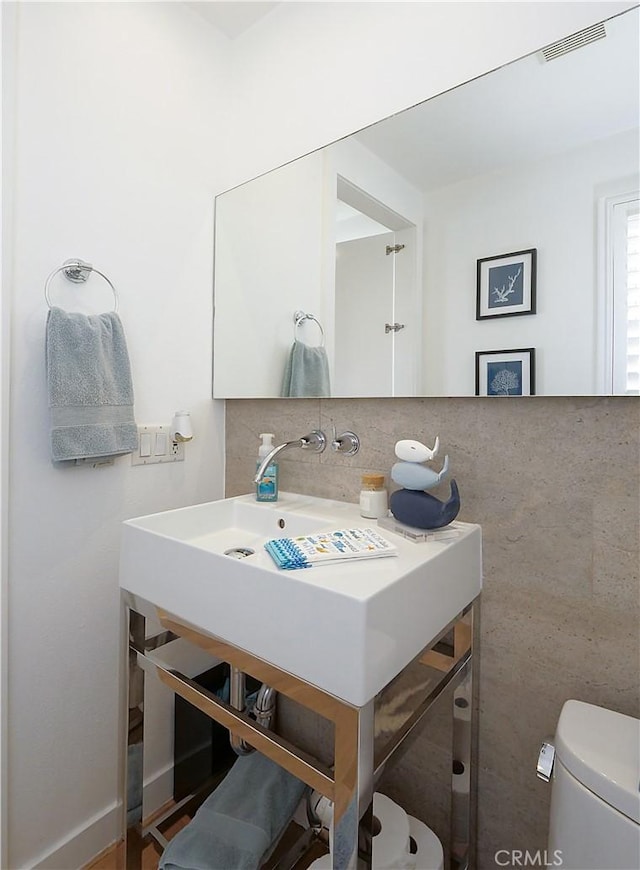 half bath with tasteful backsplash, visible vents, and toilet