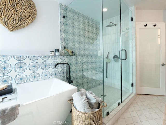 bathroom featuring a sink, tile walls, a freestanding bath, tile patterned floors, and a stall shower