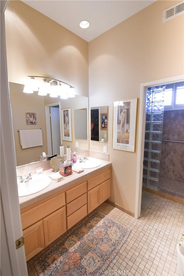 bathroom featuring double vanity, a sink, visible vents, and tile patterned floors