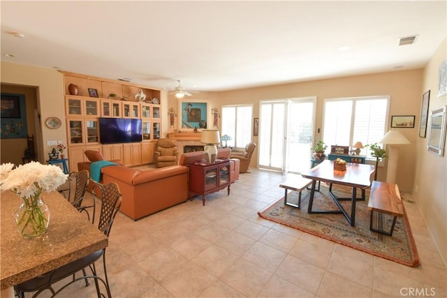 living area featuring light tile patterned floors, visible vents, and a ceiling fan