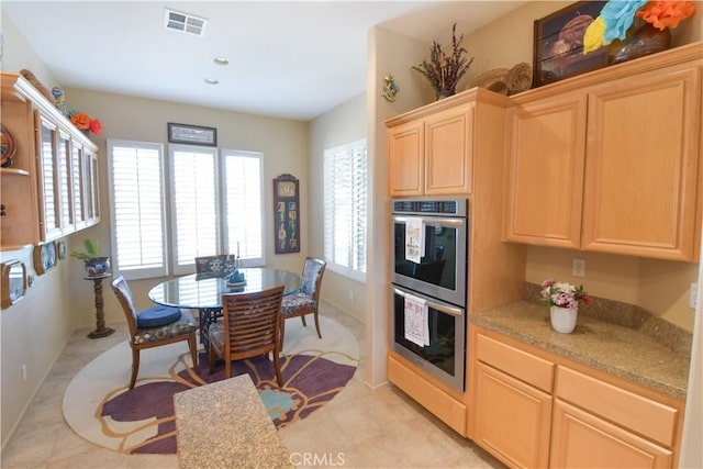 kitchen featuring stainless steel double oven, light brown cabinets, visible vents, and baseboards