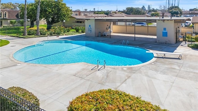 community pool with a patio area, a residential view, and fence