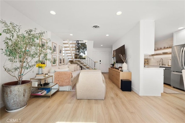 living area with stairway, light wood-type flooring, visible vents, and recessed lighting