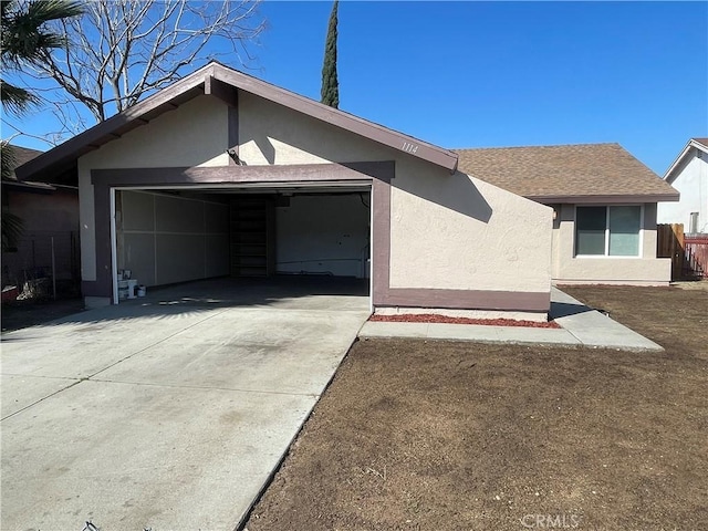 view of front of property featuring a shingled roof, concrete driveway, an attached garage, and stucco siding