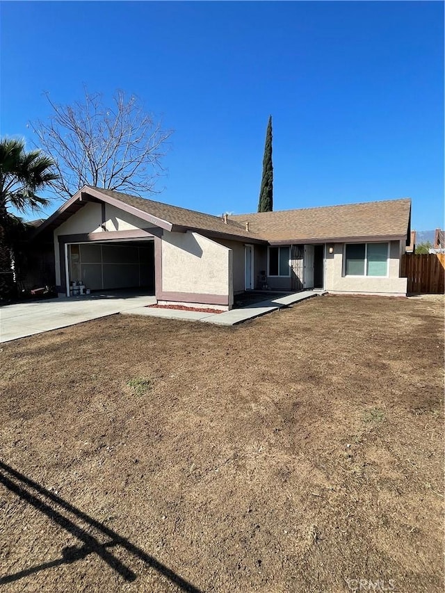 ranch-style house with a garage, concrete driveway, stucco siding, fence, and a front yard