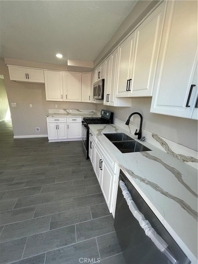 kitchen featuring light stone counters, recessed lighting, a sink, white cabinets, and black appliances