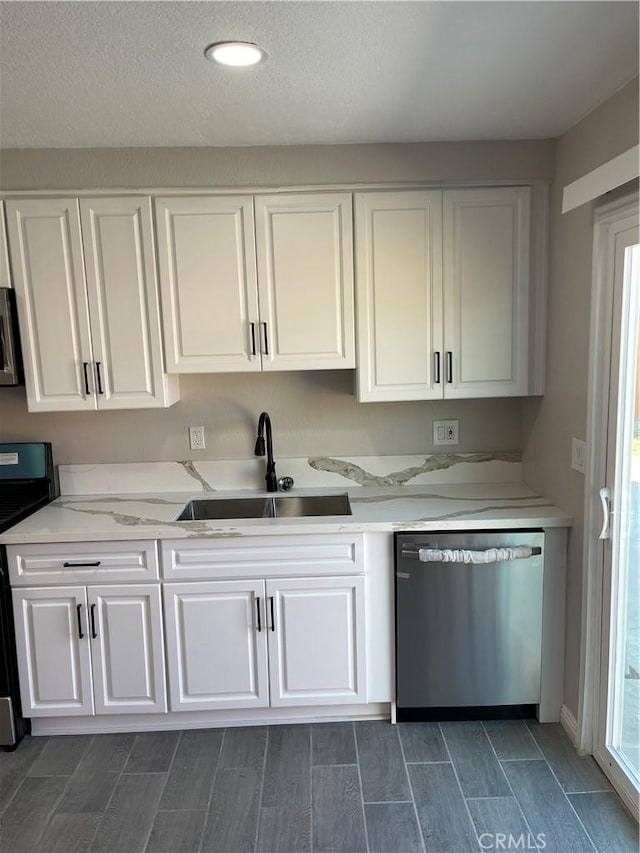 kitchen featuring white cabinets, light stone counters, stainless steel appliances, and a sink