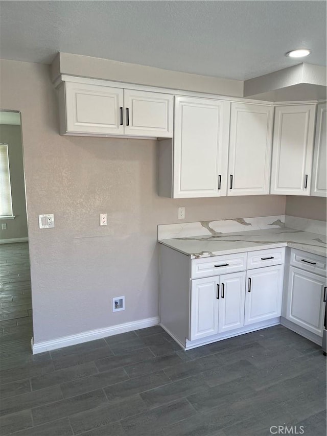 kitchen featuring dark wood-style floors, white cabinetry, and light stone countertops