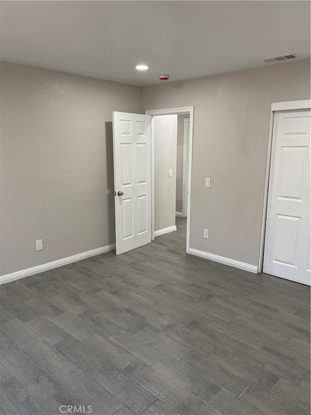 spare room with dark wood-type flooring, recessed lighting, visible vents, and baseboards