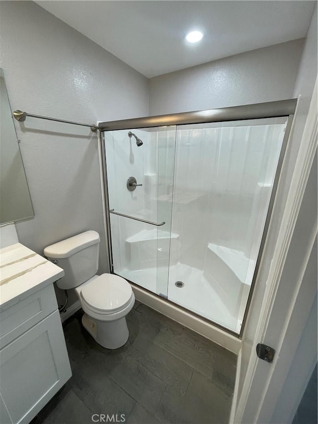 bathroom featuring a stall shower, vanity, toilet, and wood finished floors