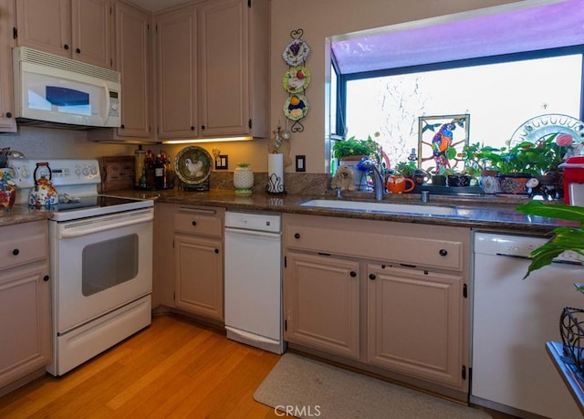 kitchen with white appliances, light wood-style flooring, and a sink