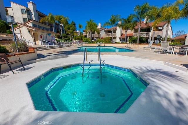 community pool featuring a residential view, a patio area, and a hot tub