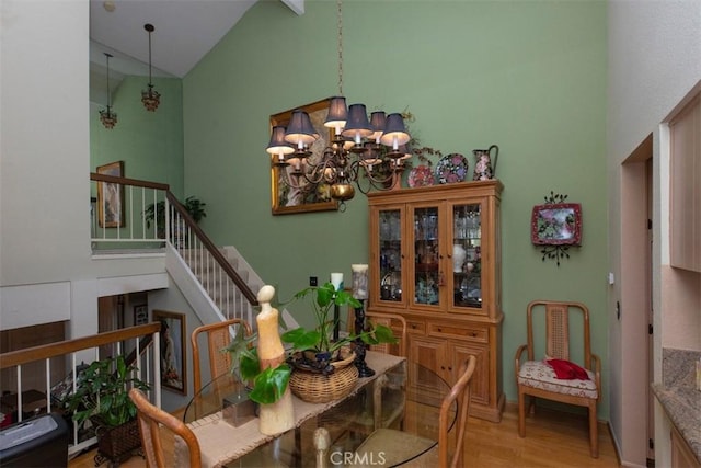 dining room featuring a chandelier, high vaulted ceiling, light wood finished floors, and stairway