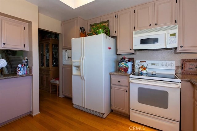 kitchen with white appliances, stone counters, and light wood-style floors