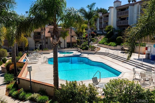 pool with a patio and a hot tub