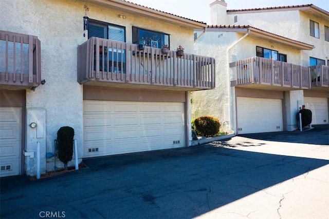 exterior space with an attached garage, driveway, a tiled roof, and stucco siding