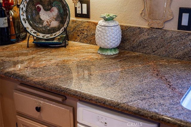 room details with white dishwasher and a textured wall