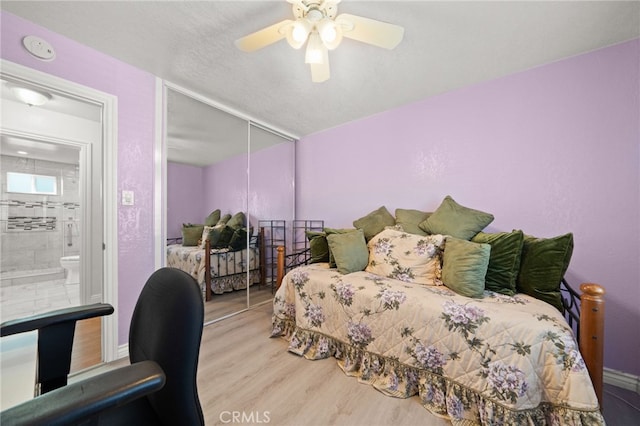 bedroom featuring baseboards, ceiling fan, wood finished floors, a textured ceiling, and a closet