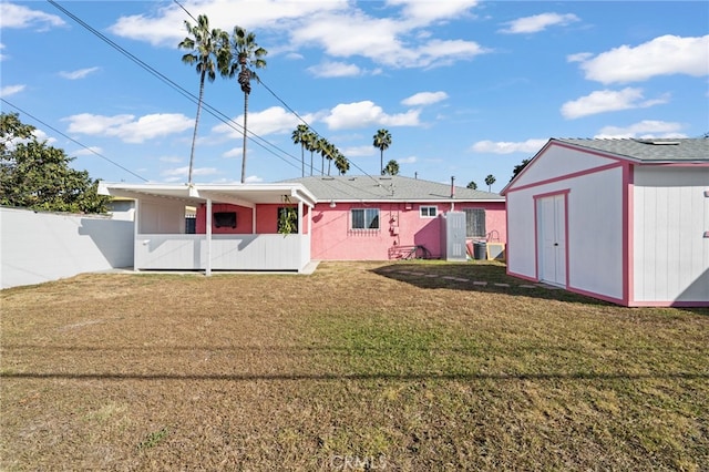 view of front of house with a front yard, fence, an outbuilding, and a storage shed