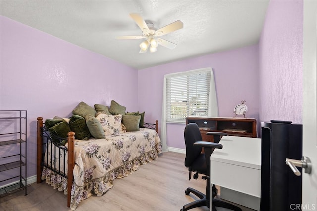 bedroom featuring a ceiling fan, a textured ceiling, baseboards, and wood finished floors