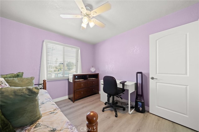 office area with baseboards, a ceiling fan, and light wood-style floors