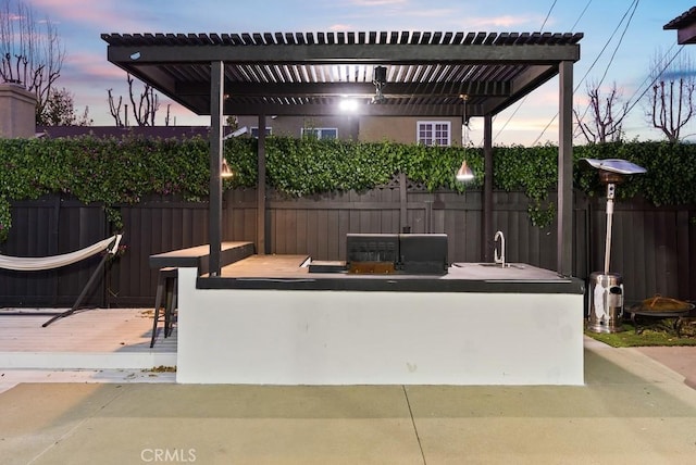 view of patio / terrace with a bar, a sink, fence, and a pergola