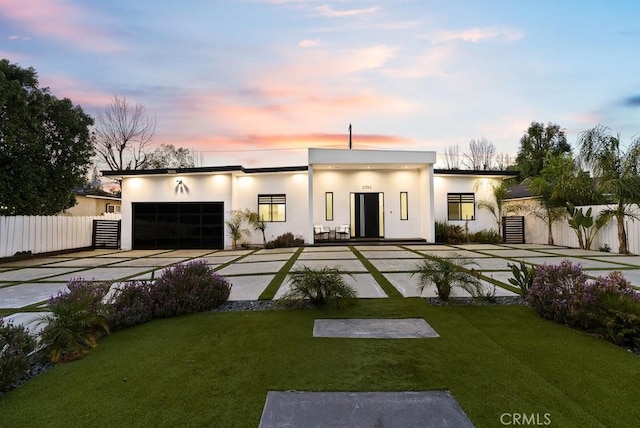 view of front of property featuring a garage, concrete driveway, a front lawn, and fence