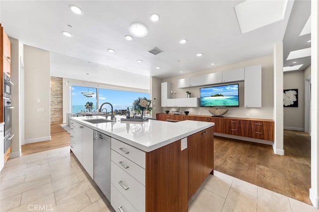 kitchen featuring a large island, a sink, light countertops, white cabinetry, and stainless steel dishwasher