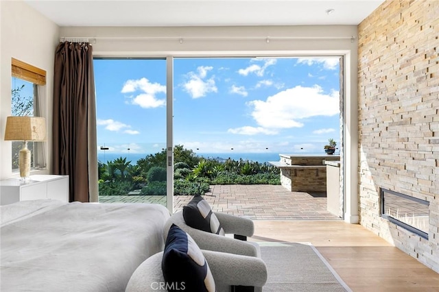 bedroom with light wood-type flooring, multiple windows, and a water view