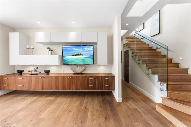 living area with light wood-style floors, baseboards, stairway, and recessed lighting