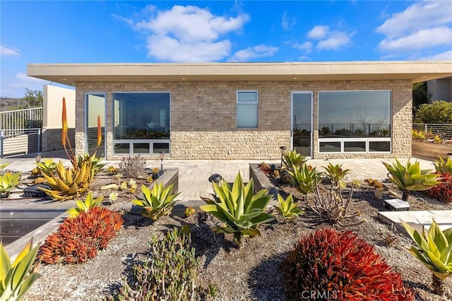 view of front facade featuring a patio, brick siding, and fence