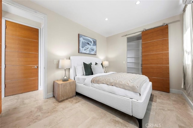 bedroom with a barn door, baseboards, a walk in closet, and recessed lighting