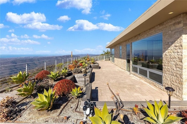 view of patio with a water view and fence