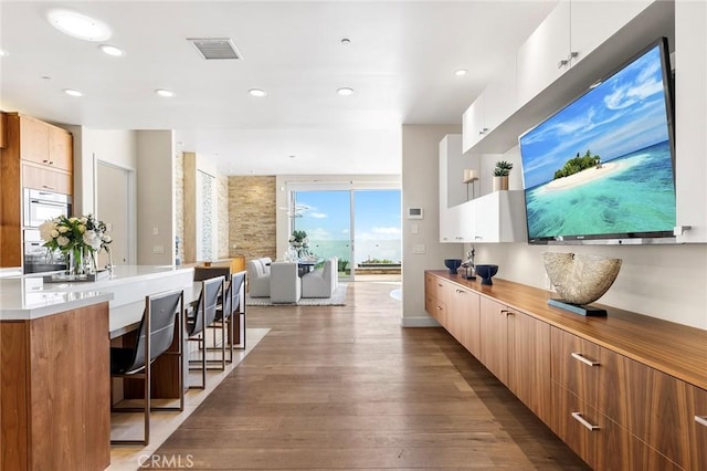 interior space with light wood-style flooring, visible vents, a kitchen breakfast bar, light countertops, and modern cabinets