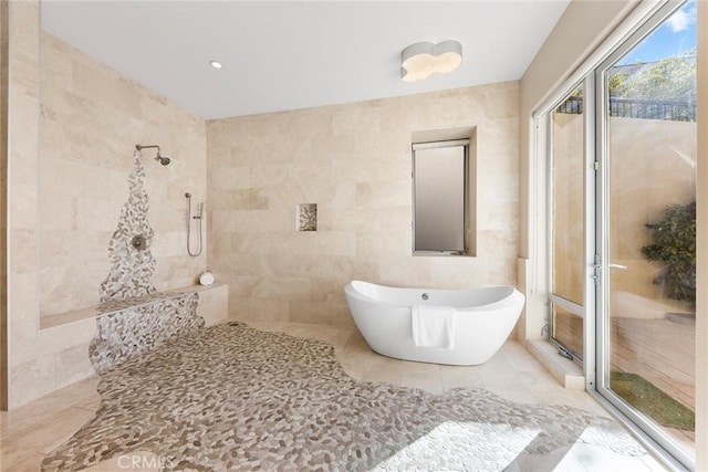 bathroom with a soaking tub, tile walls, and tiled shower