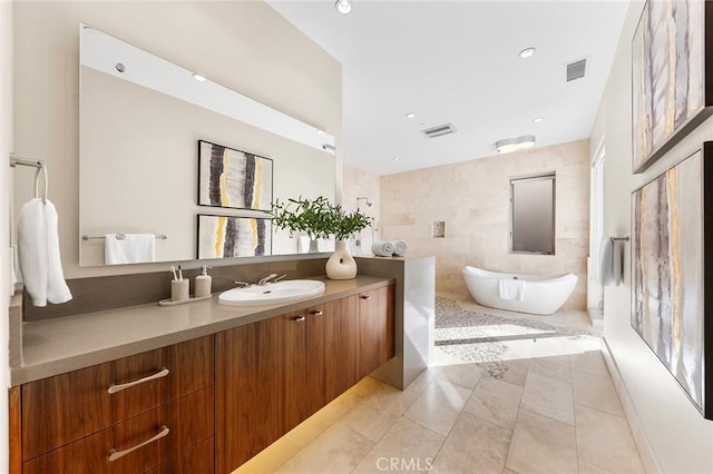 bathroom with a soaking tub, vanity, visible vents, and tile patterned floors