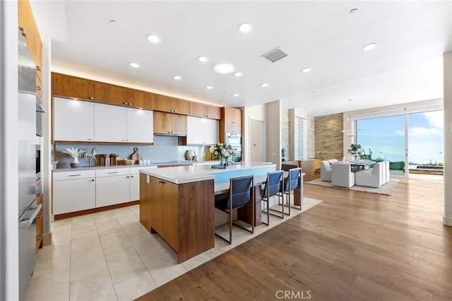 3355 Alta Laguna Blvd, Laguna Beach, CA 92651 - kitchen with a kitchen island, white cabinets, light countertops, open floor plan, and a kitchen bar