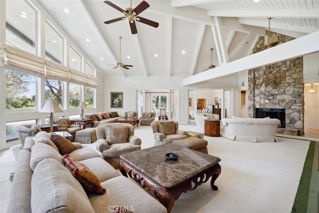 living room featuring high vaulted ceiling, beamed ceiling, and a stone fireplace