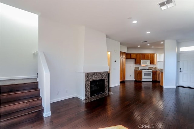 unfurnished living room featuring dark wood finished floors, recessed lighting, visible vents, baseboards, and stairs