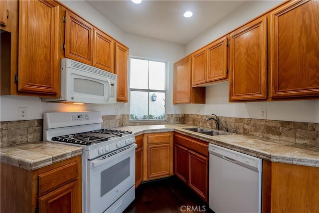 kitchen featuring white appliances, recessed lighting, a sink, and brown cabinets