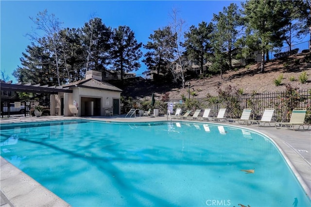 community pool with an outbuilding, fence, and a patio