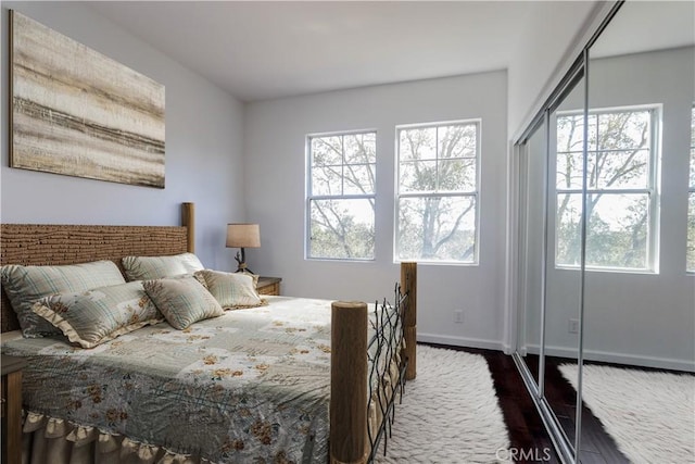 bedroom featuring dark wood-style floors, multiple windows, and baseboards