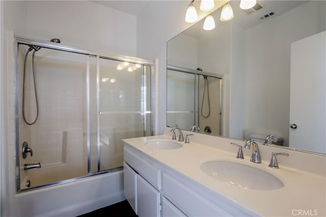 full bathroom with double vanity, combined bath / shower with glass door, a sink, and visible vents