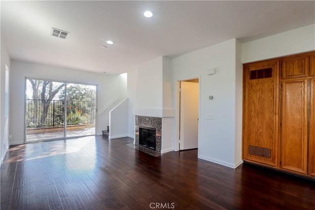 unfurnished living room featuring a tile fireplace, recessed lighting, visible vents, baseboards, and dark wood-style floors